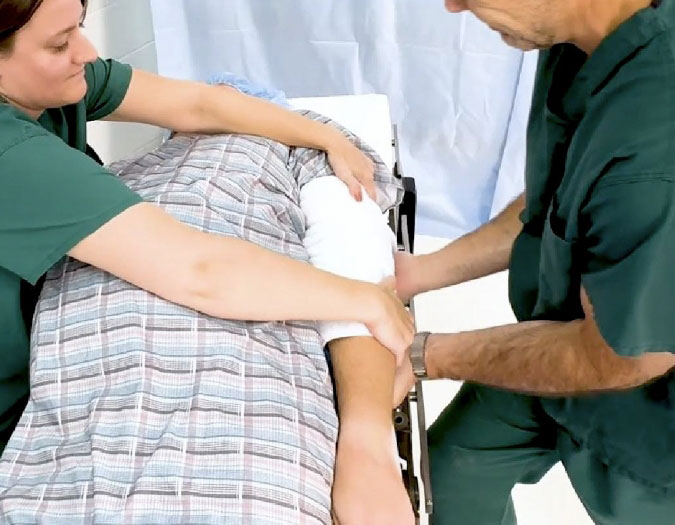 two surgeons tucking a towel under a patient's arm